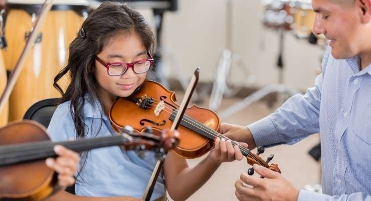 Girl with teacher learning how to play violin