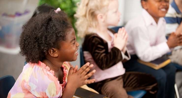 Young kids at church with hands in prayer