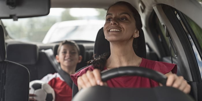 happy-soccer-mom-transporting-kid-to-football-practice-in-her-car-picture-id1128240897