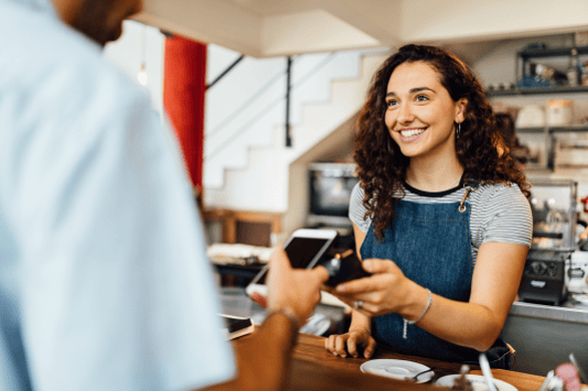 Female customer at a coffee shop paying with gift card on her phone