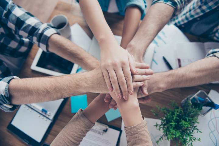 Employees' hands stacked together in a team huddle