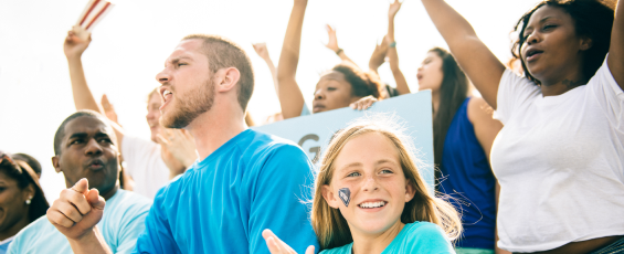 Booster club members and fans cheering at a game