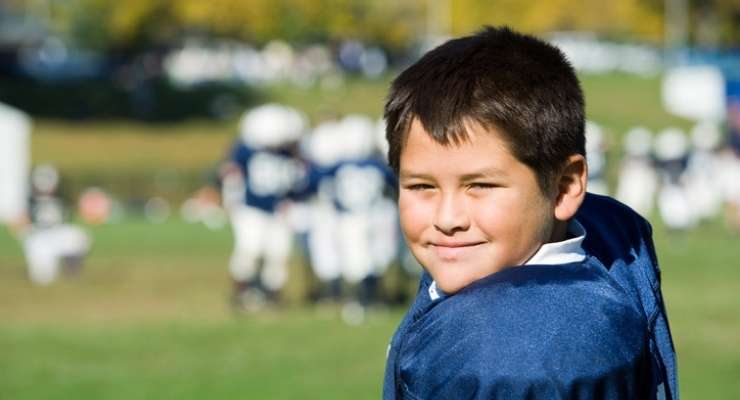 child in football uniform smiles at the camera