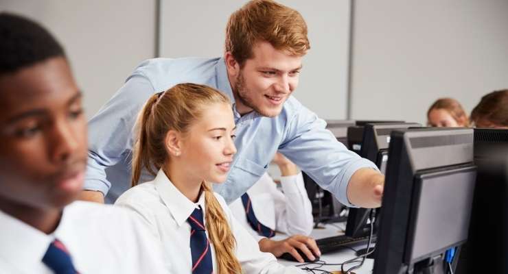 private school teacher shows a student how to do something on a computer